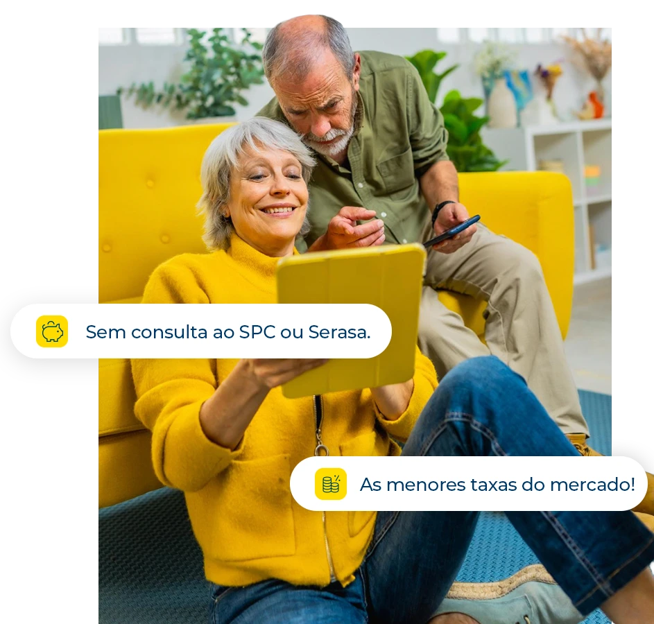 Casal de idosos sorrindo enquanto utiliza um tablet em uma sala iluminada, com pílulas flutuantes indicando "Sem consulta ao SPC ou Serasa" e "As menores taxas do mercado".